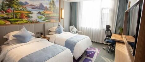 A hotel room with two beds, a desk, a chair, a TV, and a large window with curtains.