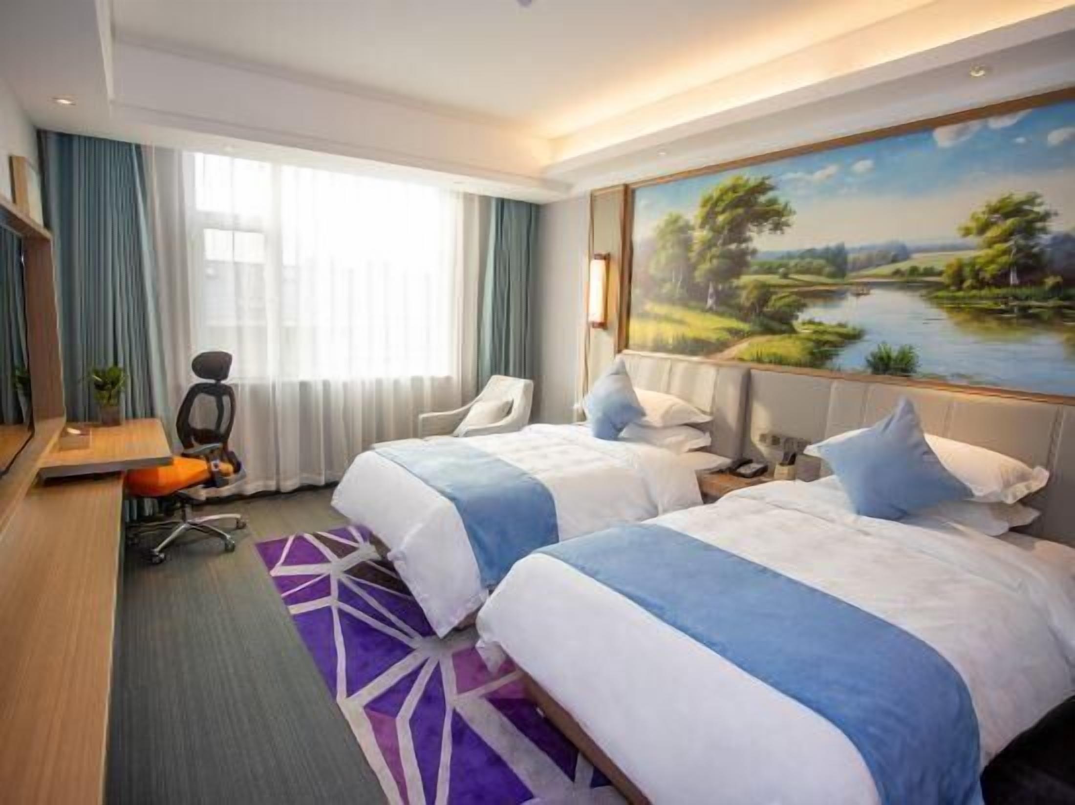 A hotel room with two beds, a desk, a chair, and a large window with curtains.