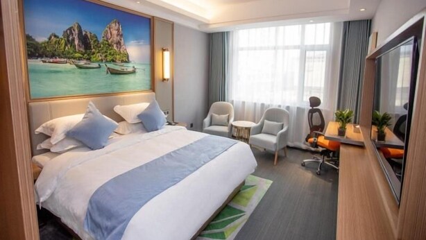 A hotel room with a large bed, a desk with two chairs, a painting of a tropical scene, and a large window with curtains. - Greentree Eastern Hotel Binzhou Zhonghai International Convention and Exhibition Center (Binzhou)