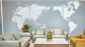 A modern living room with a world map on the wall, a light green sofa, a yellow armchair, and a coffee table with flowers. - Greentree Eastern Hotel Binzhou Zhonghai International Convention and Exhibition Center (Binzhou)