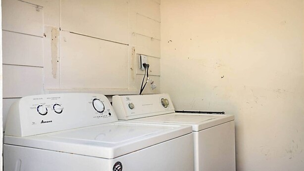 A laundry area with two white Amana washers and dryers, a power outlet on the wall, and a plain white wall. - Steps to Beach & Downtown! Private Patio & Parking (Lake Worth)