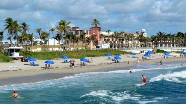 A beach with palm trees, beach umbrellas, and a lifeguard tower. - Steps to Beach & Downtown! Private Patio & Parking (Lake Worth)