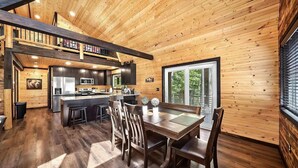 A spacious kitchen with dark wooden cabinets, a stainless steel refrigerator, and a large island with bar stools.