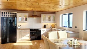 Una cucina moderna con forno integrato, frigorifero e zona pranzo con tavolo e sedie.