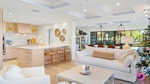 Een moderne woonkamer met een witte bank, een salontafel en een eethoek met houten stoelen.