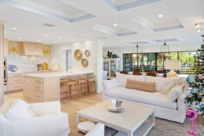 Un salon moderne avec un canapé blanc, une table basse et un coin repas doté de chaises en bois.