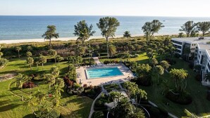 Een resort met een zwembad, palmbomen en uitzicht op de oceaan.