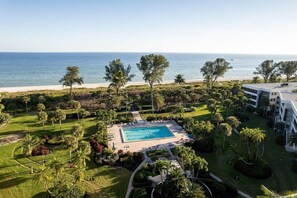 A resort with a swimming pool, palm trees, and a view of the ocean.