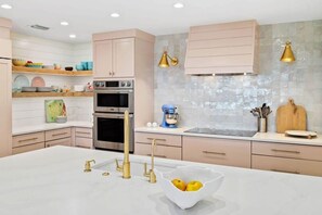 Una cocina moderna con una isla central, horno empotrado y electrodomésticos de acero inoxidable.