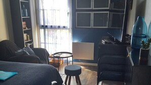 Un espacio habitable compacto con cama, escritorio, silla, una mesita y un mueble para guardar cosas.