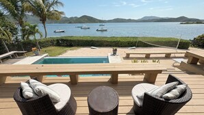 A poolside area with wicker furniture, a pool, and a view of boats on the water.