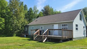 A single-story house with a front deck and a small staircase leading to the front door. - Northwoods Cabin near Upper Red Lake (Kelliher)