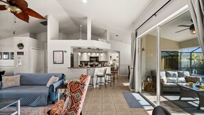 Een moderne, open woonruimte met keuken, eethoek en balkon met buitenmeubilair.