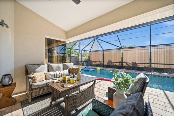 Un patio interior con piscina, mobiliario de mimbre y vistas al exterior.