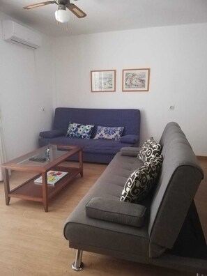 A living room with a sofa, a coffee table, and a ceiling fan.