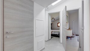 A modern hotel room with a large wardrobe, a bed with a white bedspread, and a small bedside table.