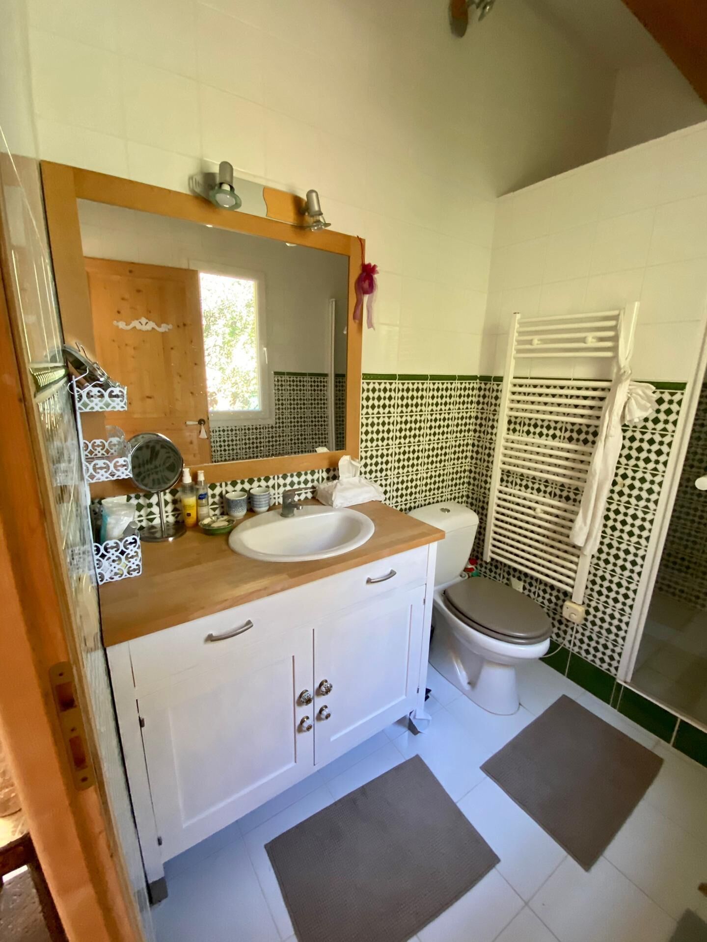 A bathroom with a wooden vanity, a sink, a toilet, and a shower area.