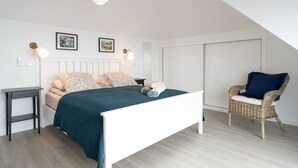A bedroom with a bed, bedside tables, a chair, and a ceiling light. - Apartment Duplex T1 - Duplex WEST (Arco da Calheta)