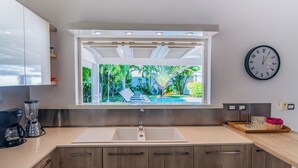 A modern kitchen with a large window, a sink, and wooden cabinets.