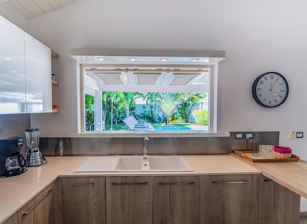 A modern kitchen with a large window, a sink, and wooden cabinets.