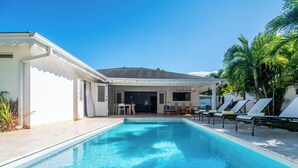 A swimming pool with lounge chairs, a covered patio, and a view of the house.