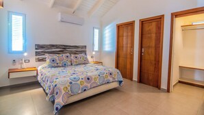 A bedroom with a bed, two bedside tables, a nightstand, a wooden wardrobe, and a built-in wardrobe.