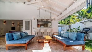 A spacious living area with a wooden coffee table, two blue sofas, and a ceiling fan.
