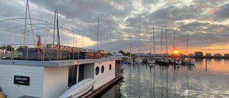 A marina with boats docked, a building labeled "Captains Boat," and a sunset in the background.