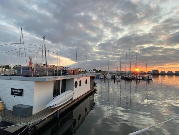 A marina with boats docked, a building labeled "Captains Boat," and a sunset in the background.