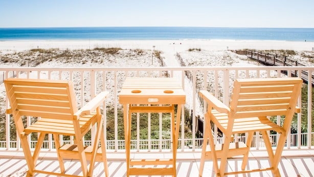 A wooden deck with two chairs and a small table overlooking a beach. - Direct Beach Front! You gotta see this view! (Gulf Shores)