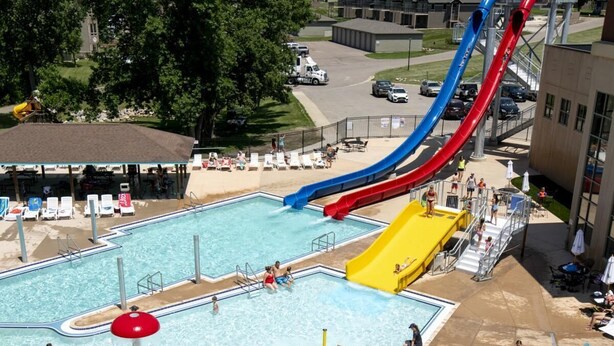Une piscine avec des toboggans, des chaises longues et des parasols.