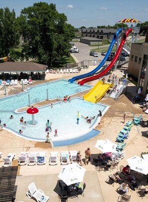 Une piscine avec des toboggans, des chaises longues et des parasols.