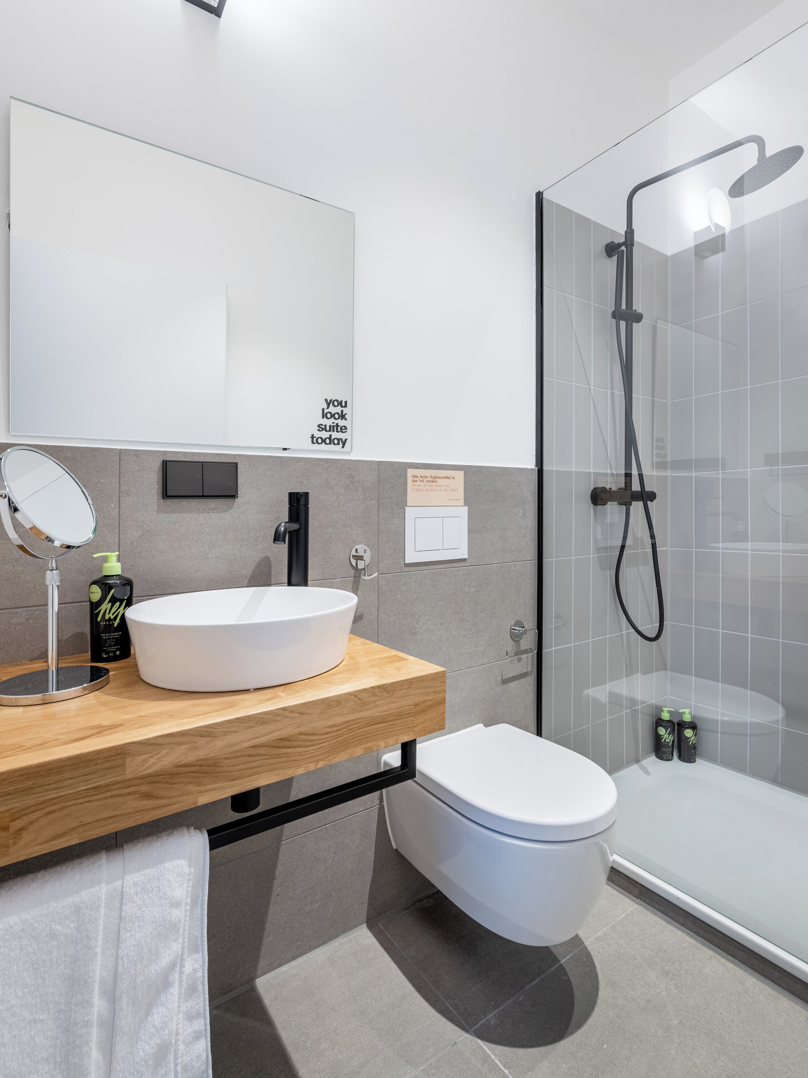 Un bagno moderno con un lavandino bianco ampio, uno specchio, un water e una cabina doccia in vetro.