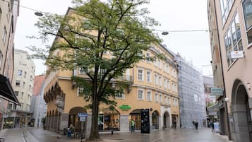 Rua arborizada com edifícios históricos, linha de bonde e calçada para pedestres.