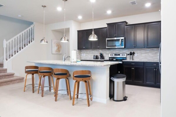 Enjoy cooking in this well-equipped kitchen with a central island, stainless steel range, and microwave.
