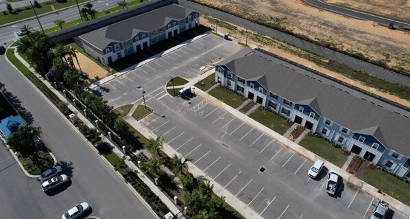 Une vue aérienne d’un parking situé à côté d’un bâtiment doté d’un toit incurvé et d’une structure à toit plat.