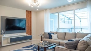 A modern living room with a flat-screen TV, a sofa, a coffee table, and a large window.