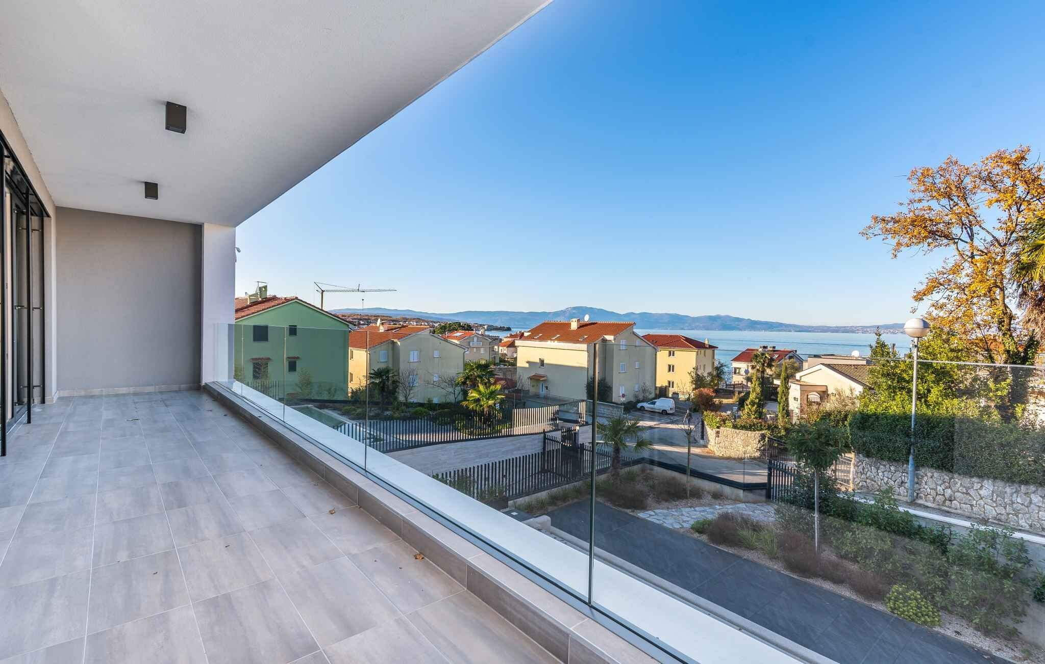 A balcony with a clear view of a residential area and a body of water in the distance.