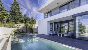 A modern house with a swimming pool, outdoor seating, and large windows. - Villa with private pool, jacuzzi and sauna (Malinska)