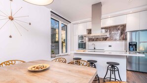 A modern kitchen with white cabinetry, a built-in oven, and a stainless steel refrigerator. - Villa with private pool, jacuzzi and sauna (Malinska)