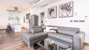 A modern living room with a grey sectional sofa, a glass coffee table, and two abstract paintings on the wall. - Villa with private pool, jacuzzi and sauna (Malinska)