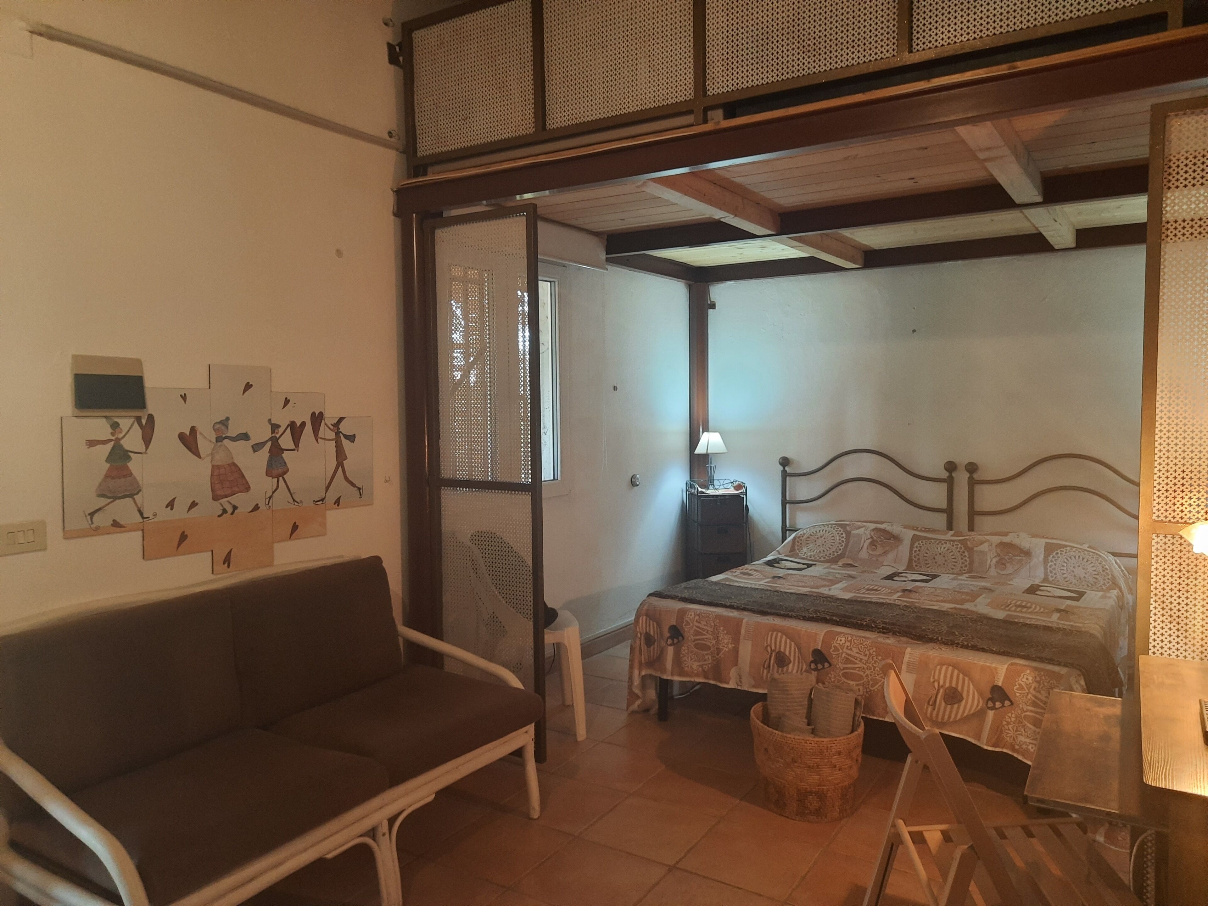 Ein Schlafzimmer mit einem Bett, einem Sofa, einem Nachttisch und einem Fenster.