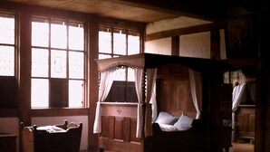 A traditional room with a wooden four-poster bed, a rocking chair, and a window with multiple panes. - Attract travellers with an engaging headline (Columbus)