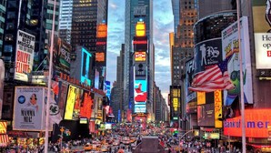 A busy urban street with tall buildings and illuminated billboards. - Attract travellers with an engaging headline (Columbus)