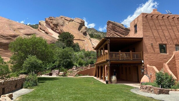 A rustic building with a balcony, surrounded by a well-maintained lawn and red rock formations in the background. - Attract travellers with an engaging headline (Columbus)