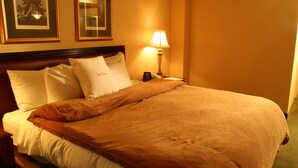 A hotel room with a bed, pillows, a lamp, and framed pictures on the wall. - Attract travellers with an engaging headline (Columbus)