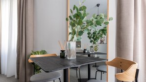 A modern dining area with a dark wooden table, grey chairs, and a large mirror reflecting the room. - Limehome Linz Friedrichstraße (Linz)