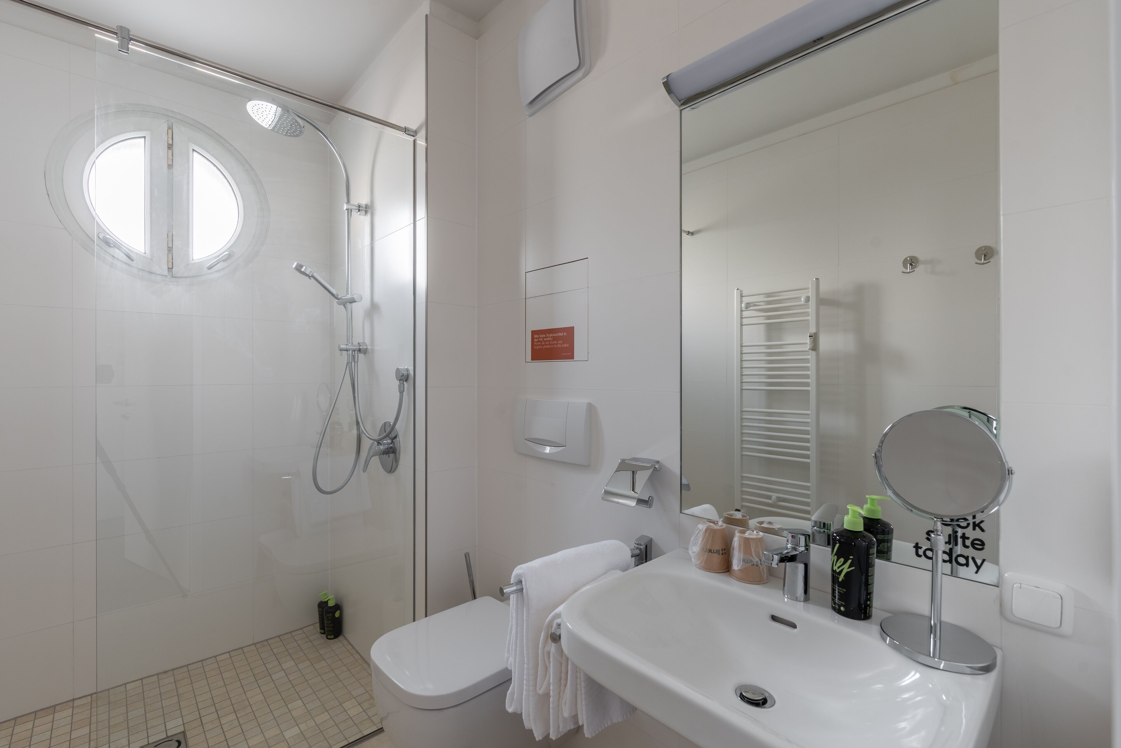 Ein modernes Badezimmer mit Dusche, Toilette, Waschbecken und einem großen Spiegel.