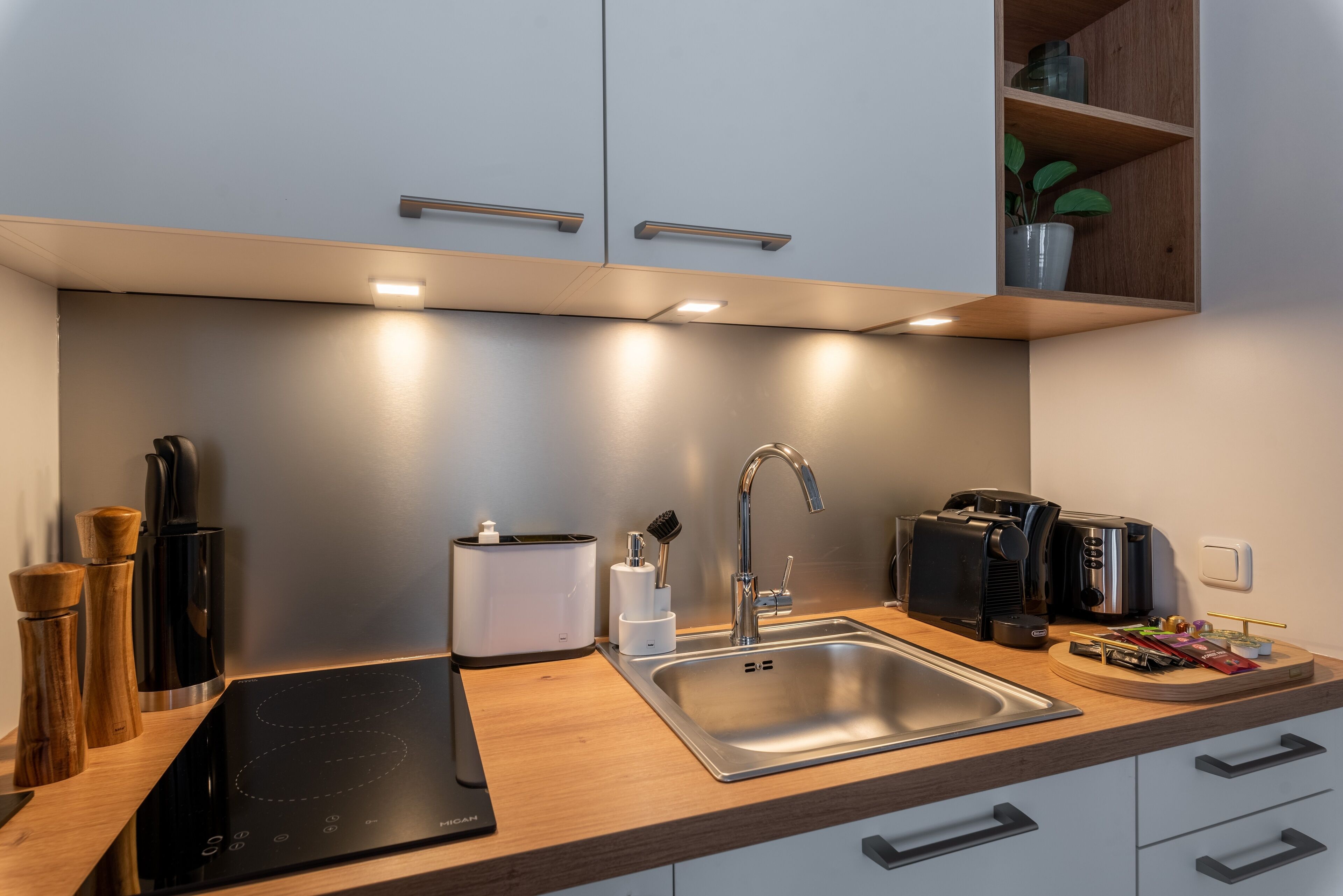 A modern kitchen with a stainless steel sink, a built-in oven, and a coffee machine.