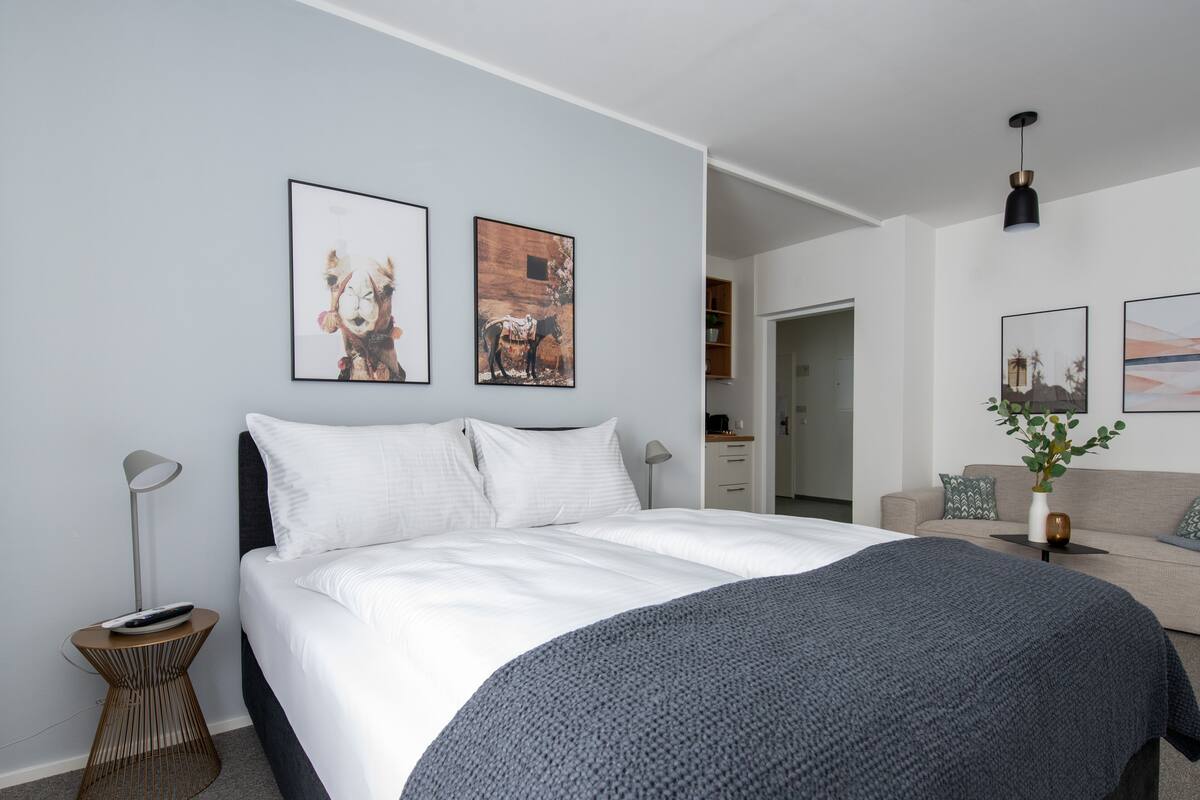 A modern bedroom with a large bed, a bedside table, a lamp, and two framed pictures on the wall.